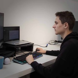 Jordan typing on a black keyboard looking at a computer