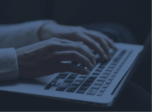 Pair of hands typing on a keyboard with a blue tint over the image