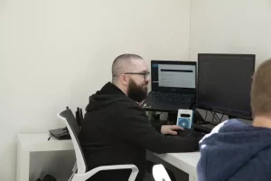 Rich sat by a black computer and monitor