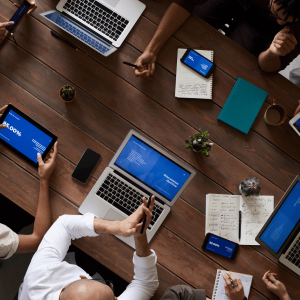 a large wooden table wit two laptops and three tablets