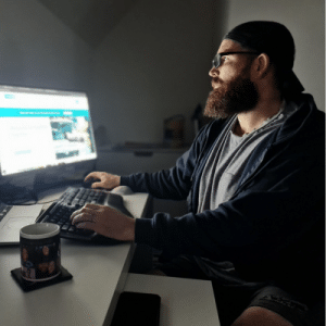 A man with a beard and glasses typing on a thick black keyboard