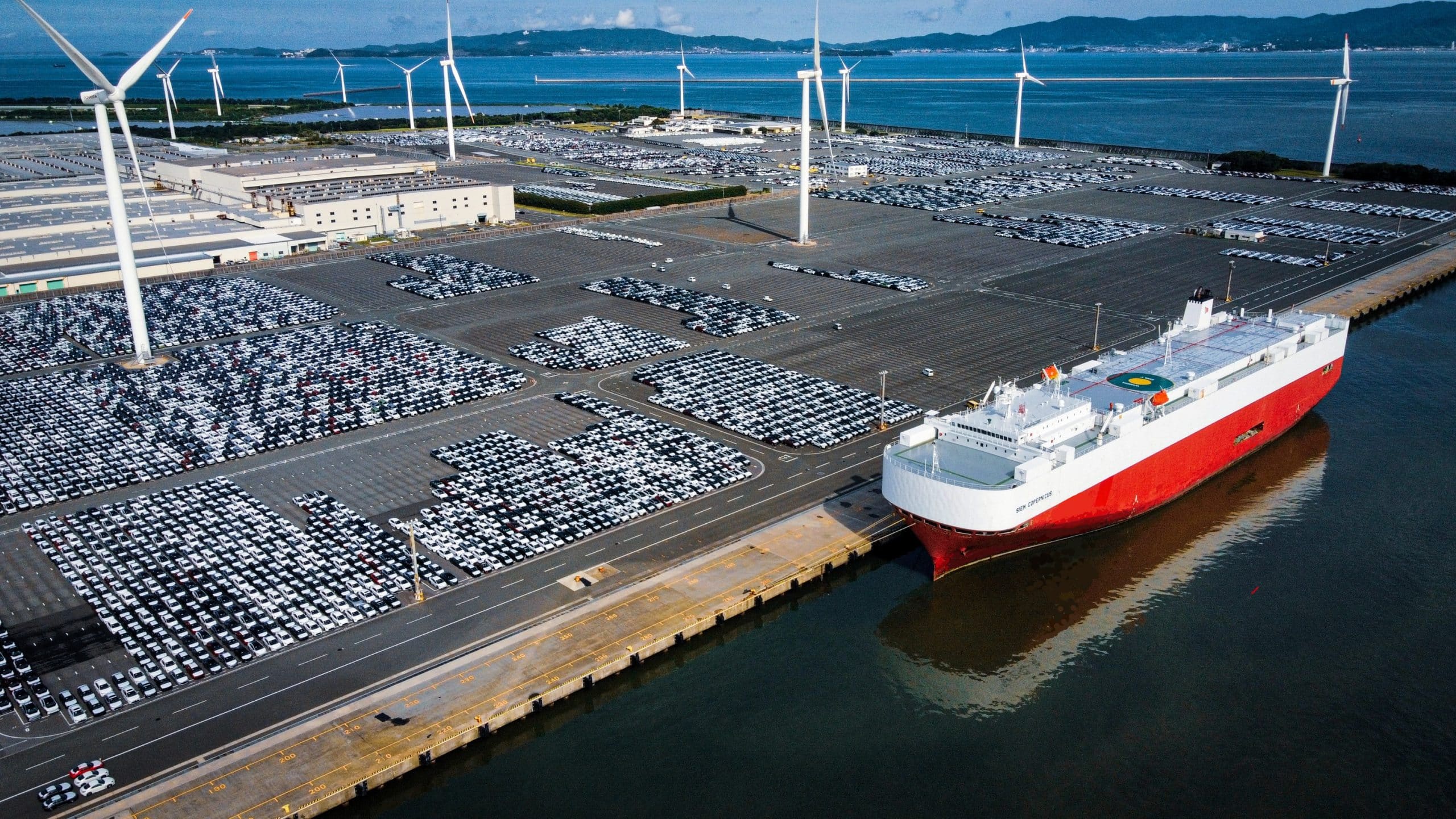 Lots of cars at a port waiting to be loaded on a ship